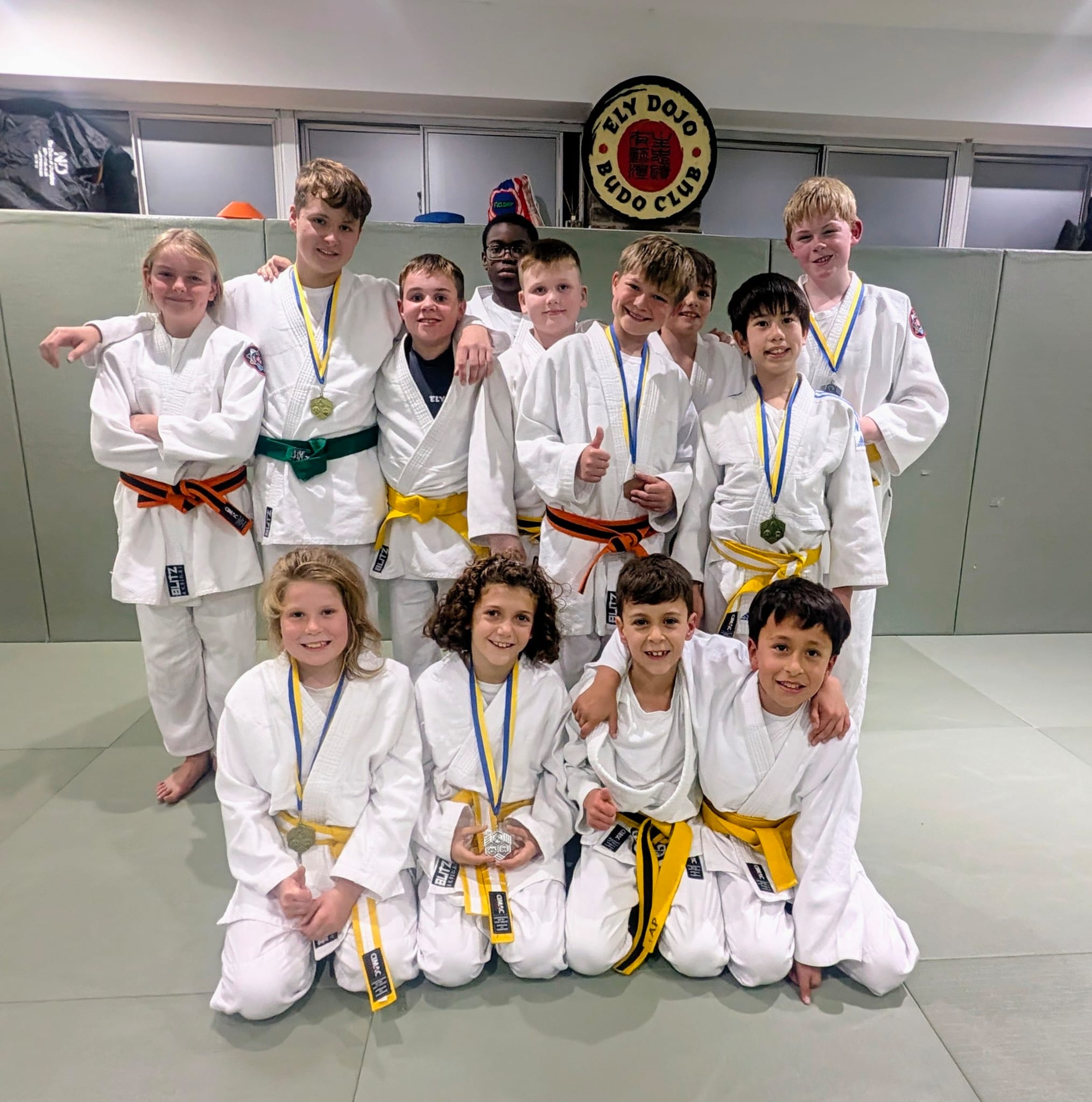 A group of Ely Dojo junior members smiling together with medals