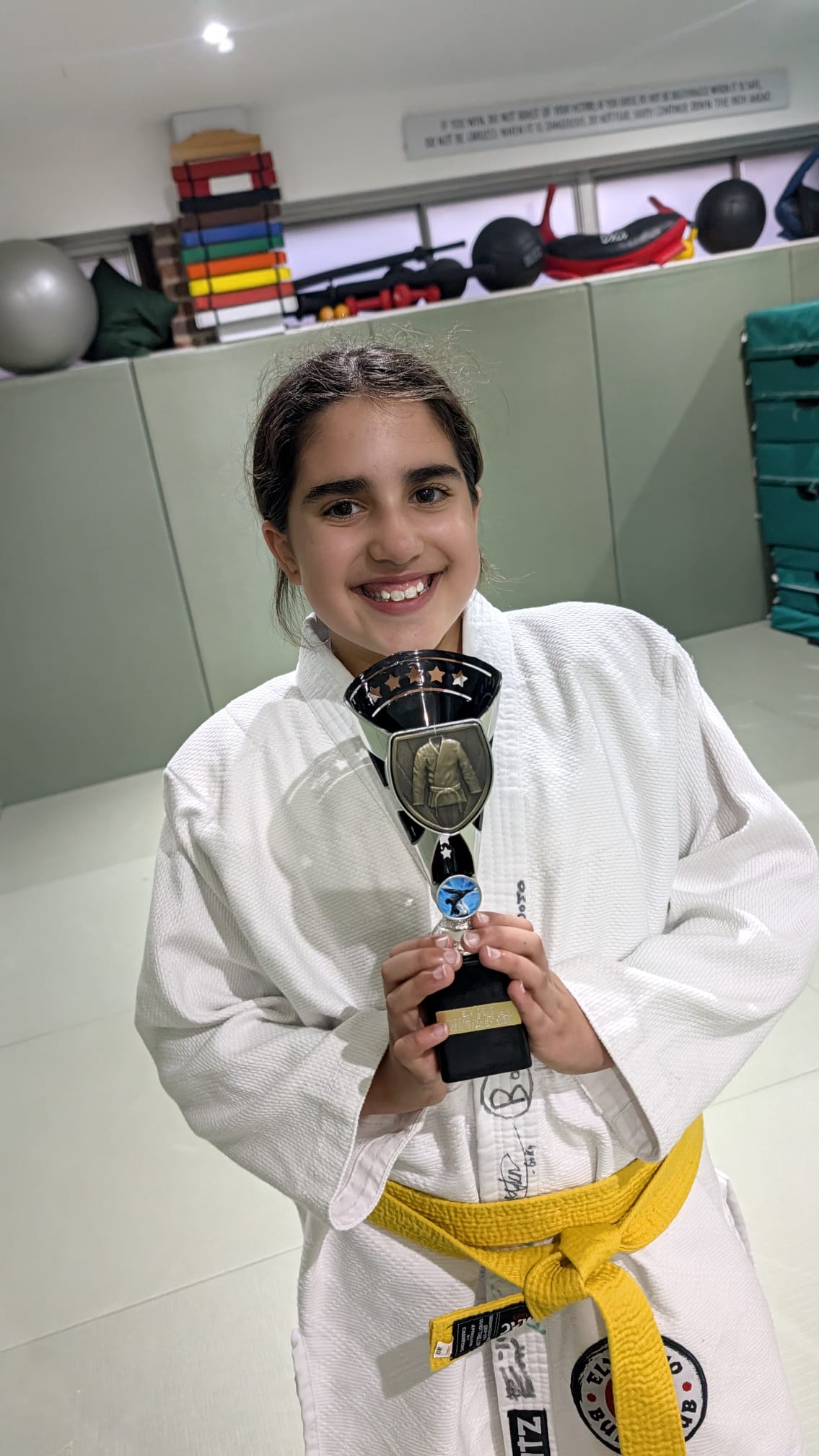 A young Ely Dojo judoka proudly holding a trophy